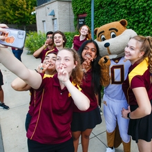 Goldy taking pictures with student